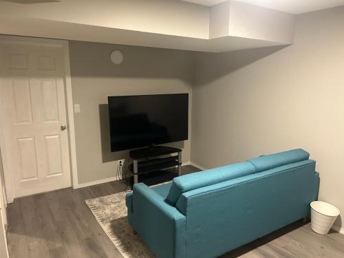 a living room with a blue couch and a flat screen tv at Basement Suite Near Edmonton Airport YEG in Edmonton