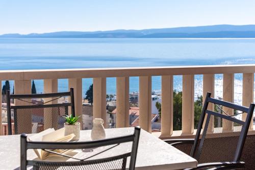 een tafel en stoelen op een balkon met uitzicht op de oceaan bij Apartments Bakota in Omiš