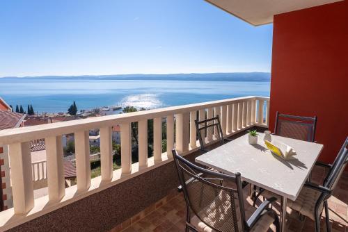 een tafel en stoelen op een balkon met uitzicht op de oceaan bij Apartments Bakota in Omiš