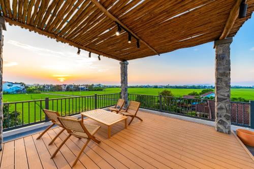a deck with a table and chairs and a sunset at Manling Retreat Hoi An in Hoi An