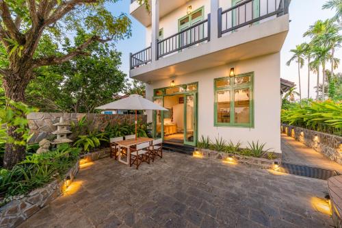 an outdoor patio with a table and an umbrella at Manling Retreat Hoi An in Hoi An