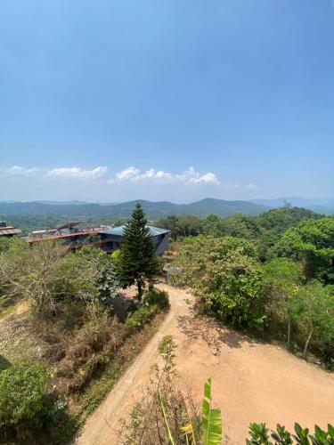 a dirt road with a house in the distance at View Point Stay in Madikeri