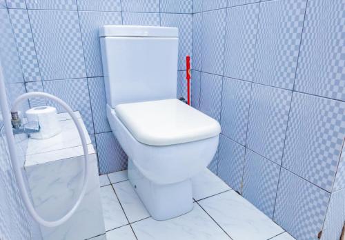 a bathroom with a white toilet in a blue tiled room at Maasai Koroga Hotel & Apartments in Mombasa