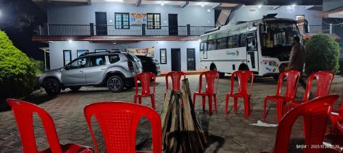 a group of red chairs and a bus and a car at View Point Stay in Madikeri