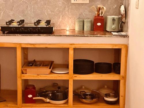 a wooden shelf with pots and pans on it at Leafyinn Elysian Escape Condo in New Delhi