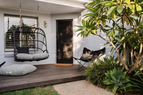 a black and white cat sitting in a chair on a porch at Sea Notes Yamba in Yamba