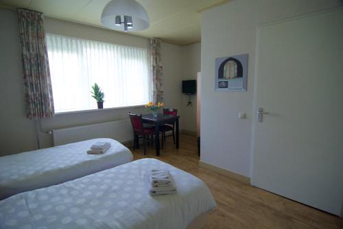 una camera d'albergo con due letti, un tavolo e una finestra di Stichting Veenloopcentrum Weiteveen a Weiteveen