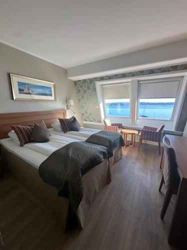 a bedroom with two beds and a table and windows at Holmen Fjordhotell in Nesbru