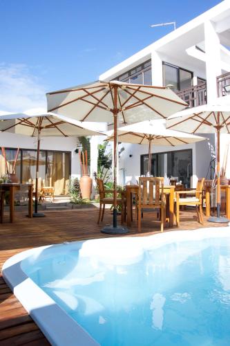 a house with a swimming pool and tables and umbrellas at Villa Alizee in Port Louis