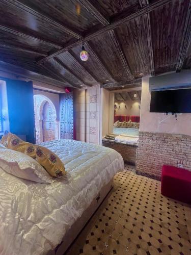 a bedroom with a large bed and a tv at Gite ECOPARADIS in Madagh