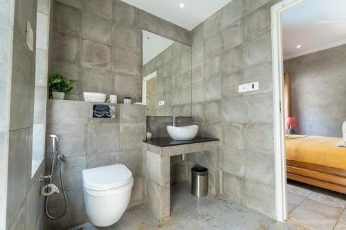 a bathroom with a toilet and a sink and a bed at Love Story Villas, Baga-Private Pool Villas in Arpora