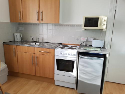 a kitchen with a white stove and a microwave at Coombe Lodge Holiday Flats in Paignton