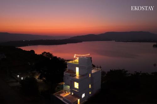 a building with a view of a lake at sunset at EKOSTAY - Eternal Wave in Lonavala