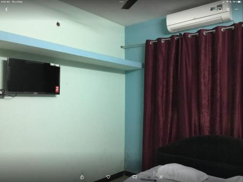 a room with a tv and a couch and a curtain at Space craft guest house in kāraikāl