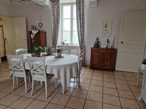une salle à manger avec une table et des chaises blanches dans l'établissement Le Logis de la Lande, à La Boissière-des-Landes