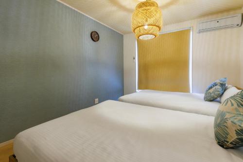 a bedroom with two beds and a window at 最大12人 那覇空港から車で15分 無料駐車場2台 南部を満喫したい方に1番のおすすめ宿 The Art Ryukyu アート琉球 in Itoman