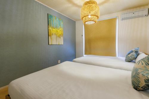 a bedroom with two beds and a chandelier at 最大12人 那覇空港から車で15分 無料駐車場2台 南部を満喫したい方に1番のおすすめ宿 The Art Ryukyu アート琉球 in Itoman