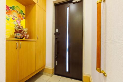 a hallway with a black door in a room at 最大12人 那覇空港から車で15分 無料駐車場2台 南部を満喫したい方に1番のおすすめ宿 The Art Ryukyu アート琉球 in Itoman
