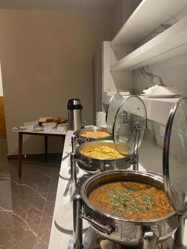 three pans of food on a counter in a kitchen at Ambrina Hotel in Islamabad