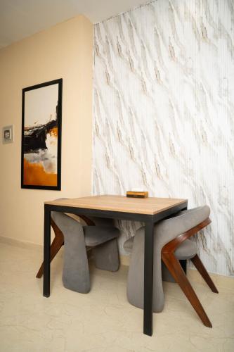 a dining room table with two chairs and a painting at Just Move Luxury 1BR APT, Near ISB Int'l AIRPT in Islamabad