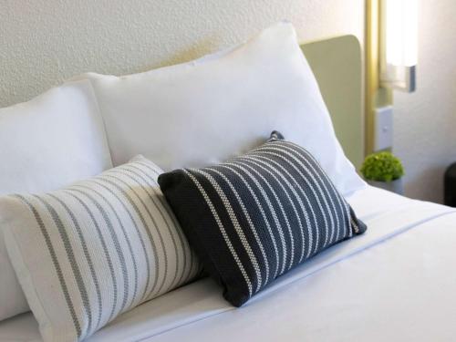 a white bed with a black and white pillow at ibis Budget Brisbane Airport in Brisbane