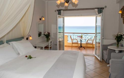 a bedroom with a bed and a balcony with the ocean at Delfino Blu Wellness Boutique Hotel in Agios Stefanos