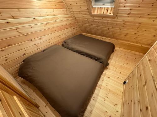 a small room with a bed in a wooden cabin at P's Wood 箱根仙石原 in Hakone