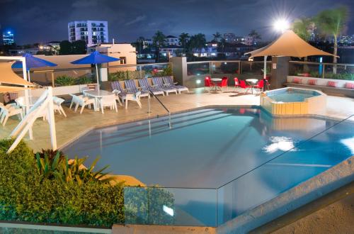 a pool on the roof of a building with chairs and umbrellas at Tiki Hotel Apartments Surfers Paradise in Gold Coast