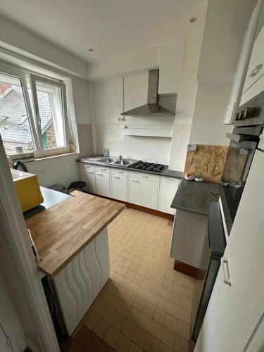 une cuisine avec des armoires blanches et un comptoir en bois dans l'établissement Appartement place Nevers, à Charleville-Mézières