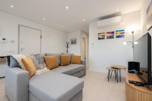 a living room with a gray couch and a television at Sunset View Apartment in Conceicao de Tavira in Tavira