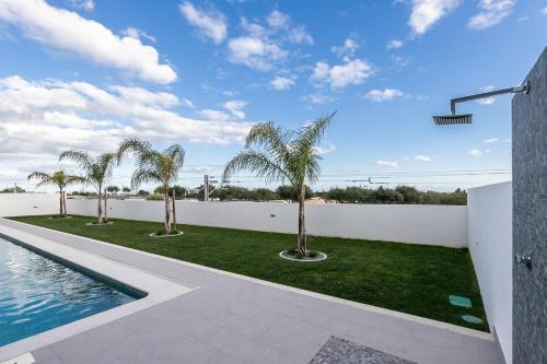 a courtyard with palm trees and a swimming pool at Sunset View Apartment in Conceicao de Tavira in Tavira