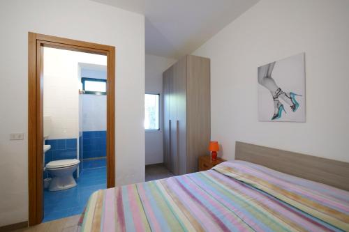 a bedroom with a bed and a bathroom with a toilet at Residence Oasis Punta Prosciutto in Punta Prosciutto