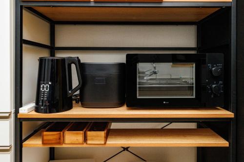 a microwave and a coffee maker on a shelf at 最大12人 那覇空港から車で15分 無料駐車場2台 南部を満喫したい方に1番のおすすめ宿 The Art Ryukyu アート琉球 in Itoman
