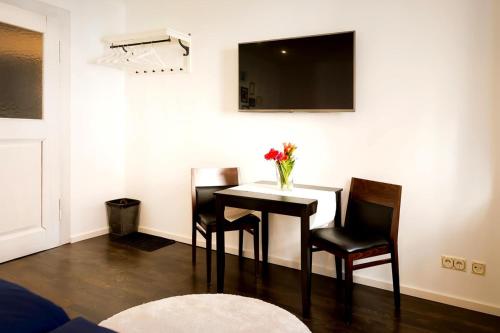a dining room table with two chairs and a vase of flowers at Ruben's Apartments in Stuttgart