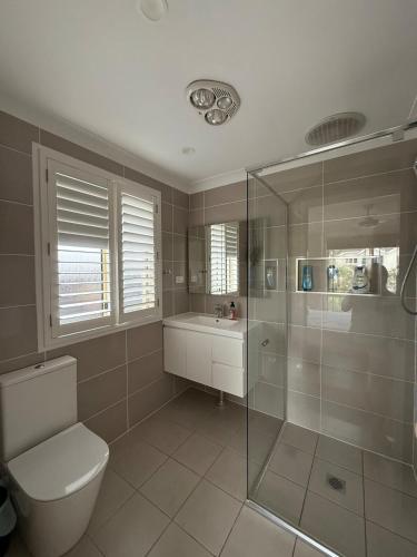 a bathroom with a shower and a toilet and a sink at Costa Casa Jervis Bay Retreat in Vincentia
