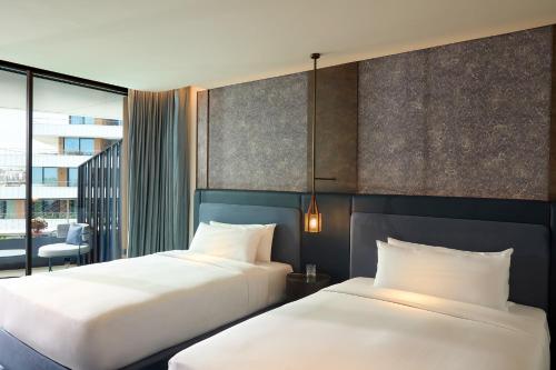 two beds in a hotel room with white pillows at SLS Barcelona in Barcelona