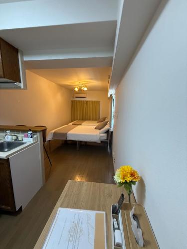 a small room with a bed and a kitchen with a sink at Camelot House in Fukuoka