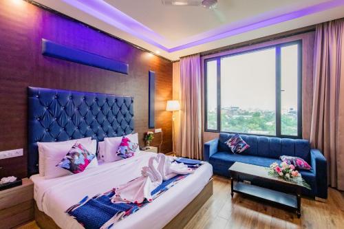 a bedroom with a large bed and a blue couch at Foxoso Fiori Hotel in Jaipur