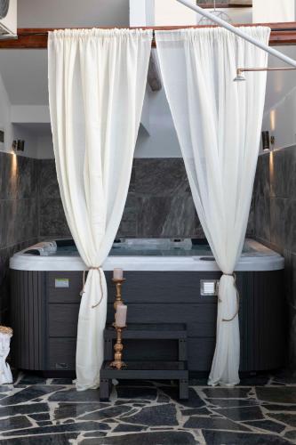 two white curtains in a bathroom with a tub at Cleopatra deluxe with jacuzzi apart in Kamilari with panoramic view in Kamilari