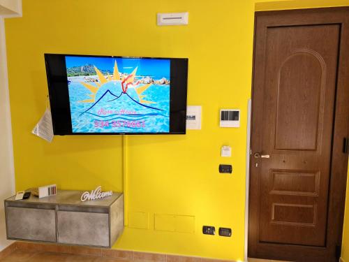 a flat screen tv hanging on a yellow wall at Rosa's house in Lipari