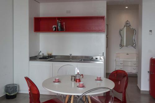 a kitchen with a white table and red chairs at Liberty Palace in Milazzo