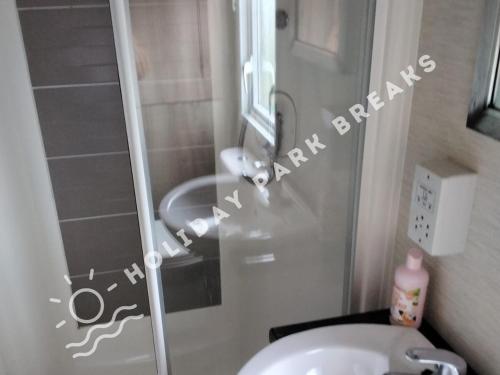 a bathroom with a toilet and a glass shower door at Valeria - Gold 3 bedroom with Garden and Parking - Seal Bay in Selsey