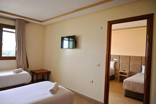 a hotel room with two beds and a mirror at Hôtel Jawharat El Jadida in El Jadida