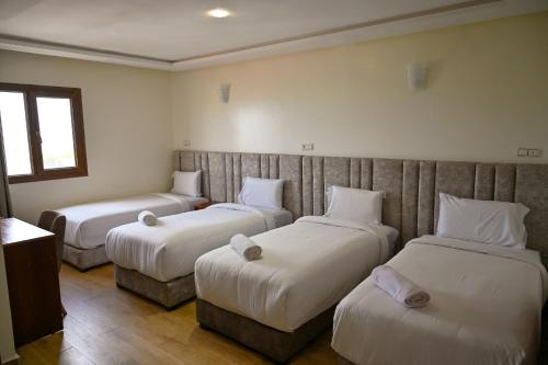 a hotel room with three beds and a window at Hôtel Jawharat El Jadida in El Jadida