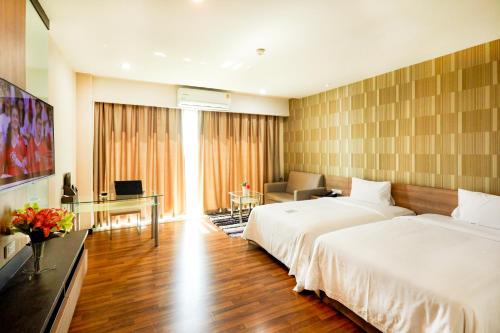 a bedroom with a large white bed and a desk at Golden City Rayong Hotel in Rayong