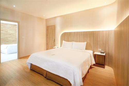 a bedroom with a large white bed and wooden walls at Golden City Rayong Hotel in Rayong