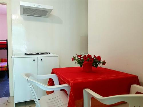 una mesa con un mantel rojo y un jarrón con flores en Casette sulla spiaggia di Punta Prosciutto, en Punta Prosciutto