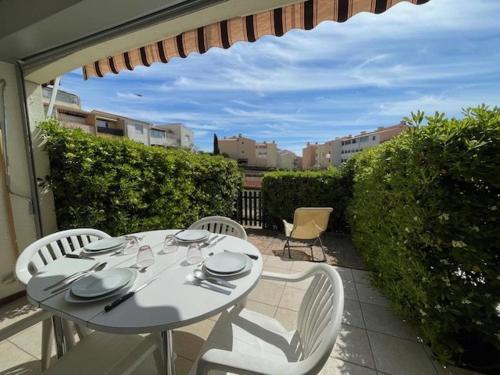 une table blanche et des chaises assises sur une terrasse dans l'établissement CAP D'AGDE Studio Cabine 046- 4 personnes Résidence avec piscine quartier Môle, au Cap d'Agde