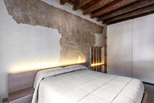 a bedroom with a white bed and a brick wall at Luxury Apartment on Piazza Erbe in Verona