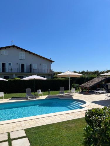 a swimming pool with chairs and umbrellas next to a building at Podere Vasella - Suite junior sx in Capranica
